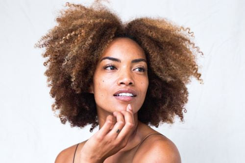 Black woman in front of white background with naturally curly hair